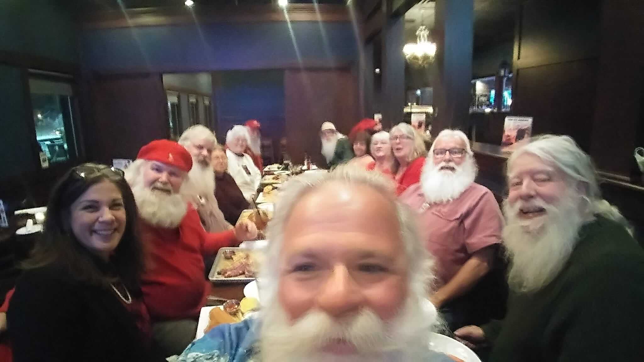 A group of men dressed as Santa Claus sitting together at a table.