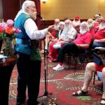 An elderly man speaking to an audience in a conference room.