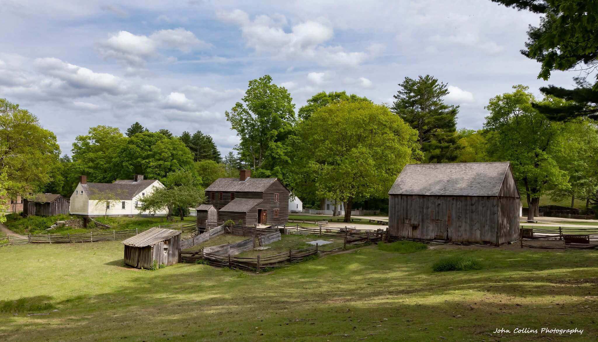 Historic rural farm buildings under cloudy sky.