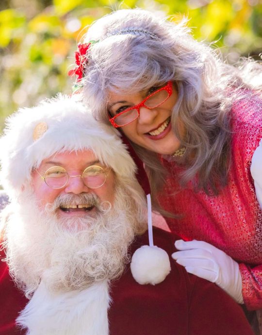 A joyful Santa Claus with a smiling woman in a festive setting.
