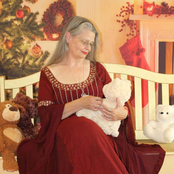 A woman in a red dress holding a baby on a crib.