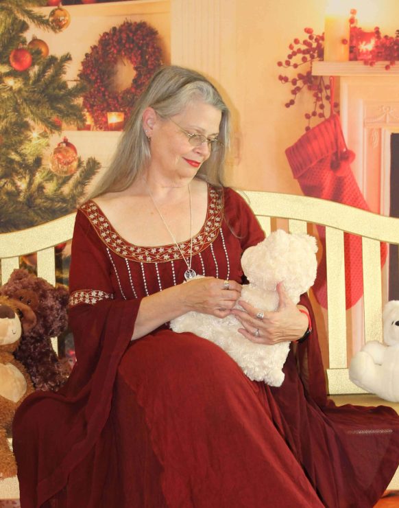 A woman in a red dress holding a baby on a crib.