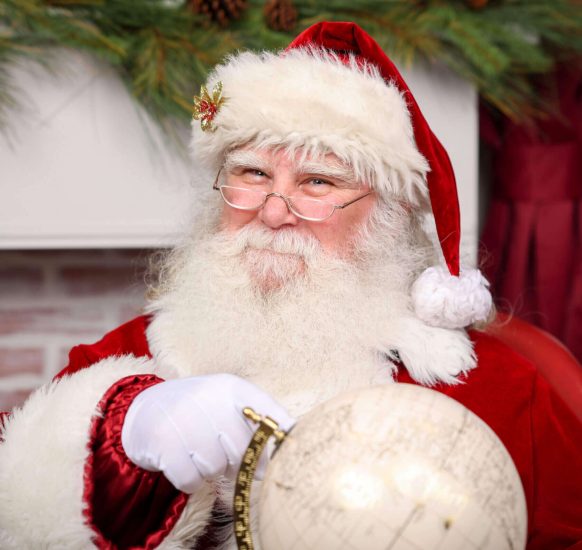 Santa Claus holding a globe and smiling warmly.