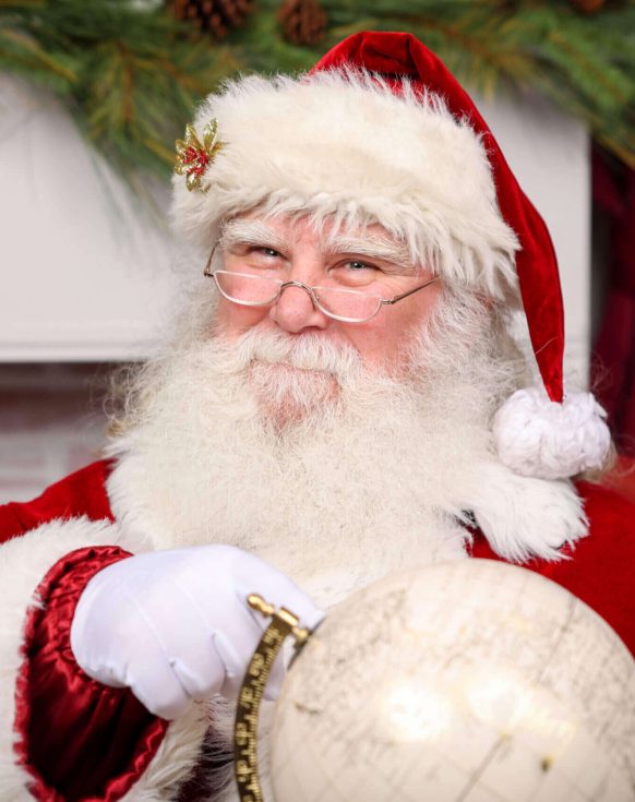 Santa Claus holding a globe and smiling warmly.